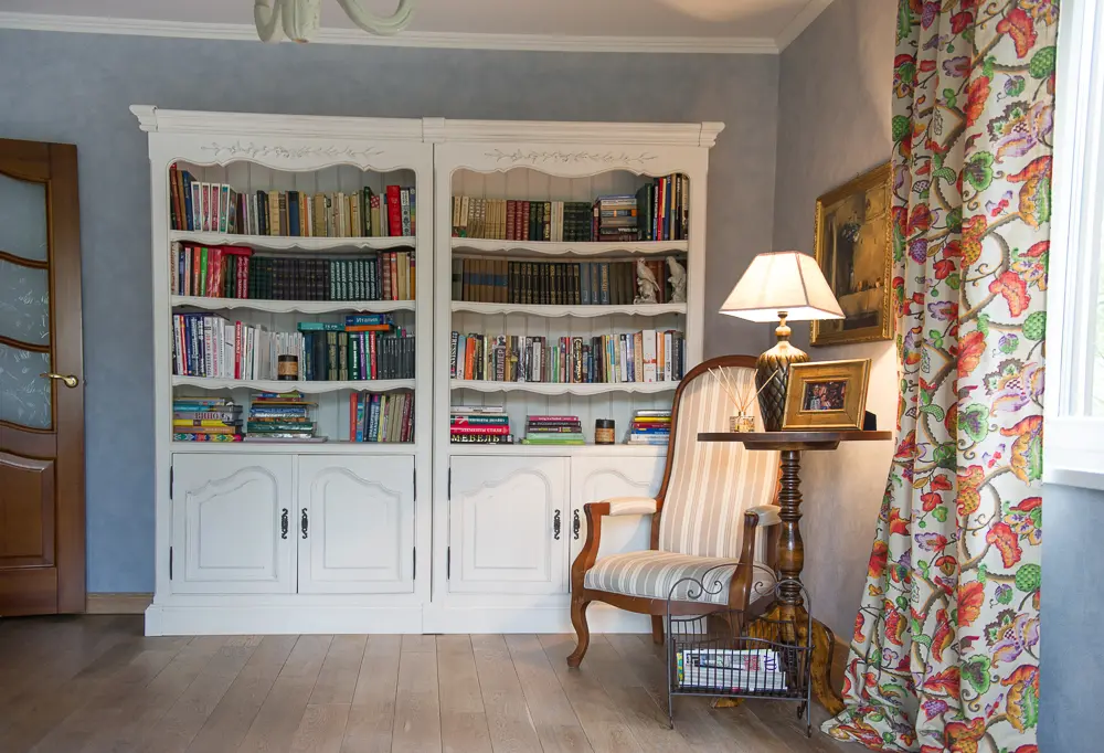 зона библиотеки в гостиной склассическим полосатым креслом, столиком-геридоном в темном дереве, массивной настольной лампой и металлической газетницей.jpg