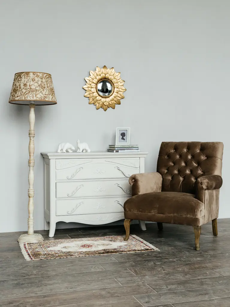 зона отдыха в гостиной с бархатным креслом темно-горчичного цвета, комодом, торшером в теплых тонах и настенным декоративным зеркалом в золотой раме.jpg