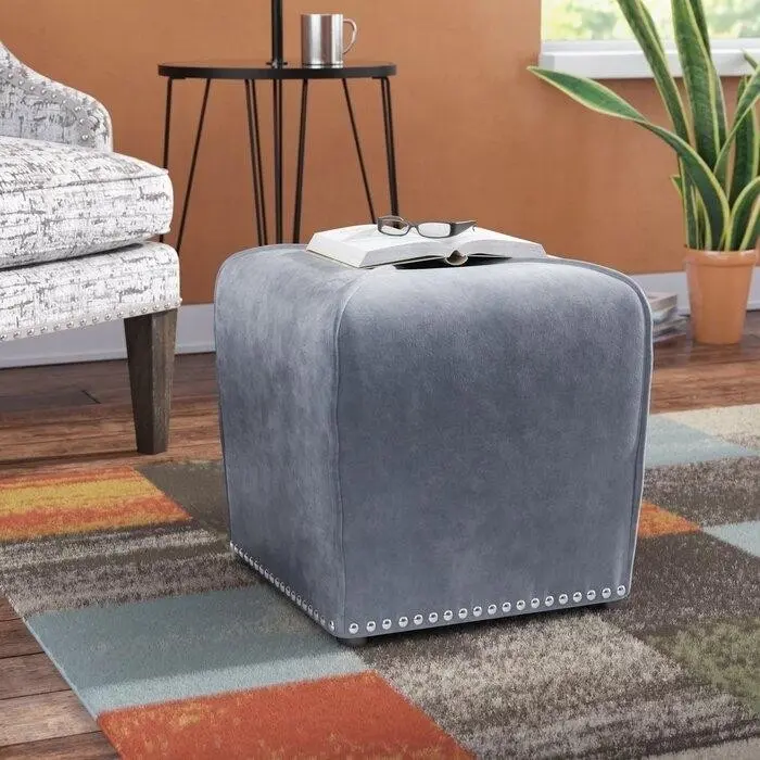 серая бархатная оттоманка в форме куба с декоративными гвоздиками по краю.jpeg