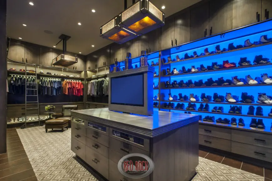 гардеробная комната с островом в центре, кожанным креслом и лестницей.jpg