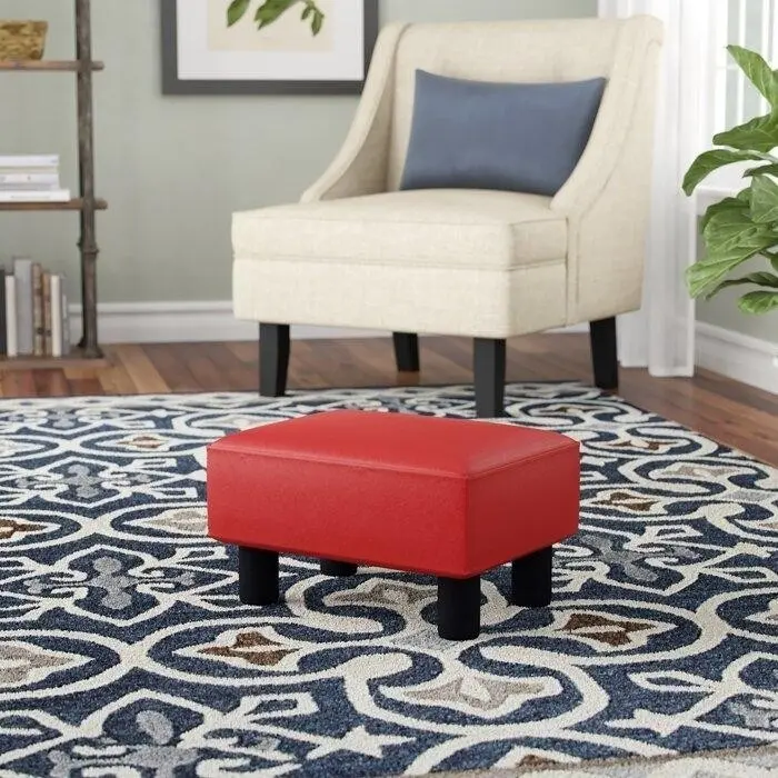 миниатюрная оттоманка из красной искусственной кожи на деревянных ножках.jpeg