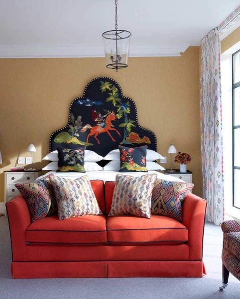 спальны с высоким изголовьем кровати с росписью и ярким двухместным диванчиком томатного цвета в изножье.jpg