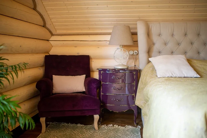 Спальня в деревянном доме с акцентным комодом и креслом